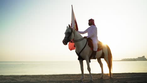Ein-Ritter-Zu-Pferd,-Der-Die-Katar-flagge-Nahe-Dem-Meer-Hält-1