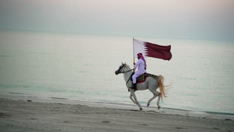 Ein-Ritter,-Der-Auf-Einem-Pferd-Reitet-Und-Die-Katar-flagge-In-Der-Nähe-Des-Meeres-Hält-1