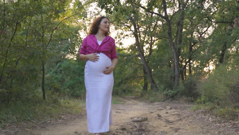 Mamá-Embarazada-Feliz-Explorando-El-Sendero-Del-Bosque-Serpenteando-Alrededor-De-Las-Raíces-Acariciando-El-Vientre