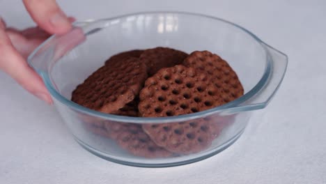 Hand-Puts-Glass-Bowl-Of-Chocolate-Cookies-On-The-Table-Then-Take-It-Away-Again