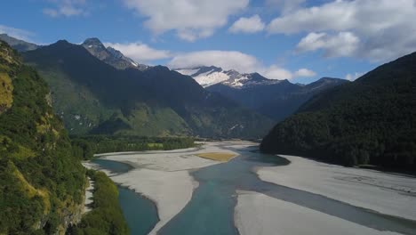Descending-pedestal-drone-shot-of-a-melting-river-in-a-large-valley-at-Mount-Aspiring-National-Park-New-Zealand