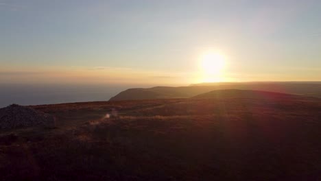 Amazing-Aerial-Drone-Shot-of-Sunrise-of-Coastal-Cliffs-with-Winding-Hiker-Path-Rock-Cairn-and-Foggy-Mountains-in-Distance-Holdstone-Down-Exmoor-Devon-UK-4K