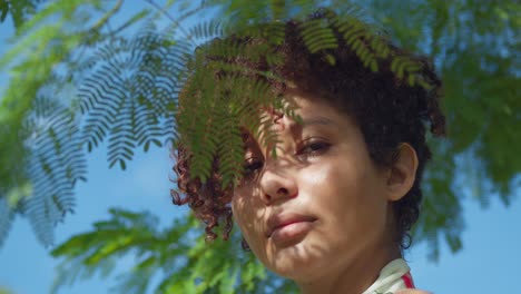 Latina-Braunäugiges-Mädchen-Gesicht-Nahaufnahme-In-Einem-Park-Mit-Blättern-Eines-Baumes-Im-Vordergrund