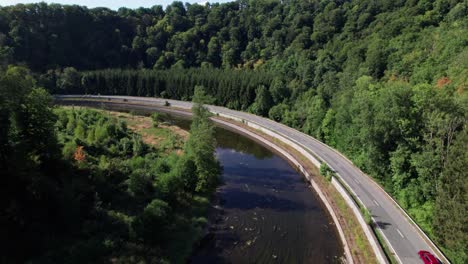 Aerial-drone-shot-of-river-adjacent-to-the-highway-in-Ardennes,-North-France