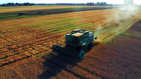 Combine-Harvester-Working-In-An-Agricultural-Field-During-Harvest-In-Lithuania---aerial-drone-shot