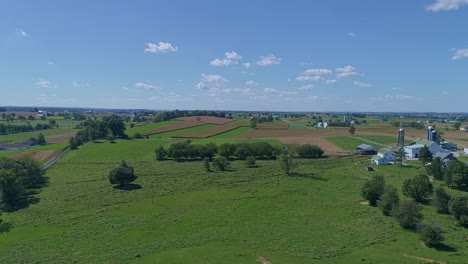Eine-Luftaufnahme-Von-Bauernhöfen,-Silos-Und-Ackerland,-Die-Bald-Mit-Einem-Amish-Pferd-Und-Einem-Buggy-Durchfahren-Werden