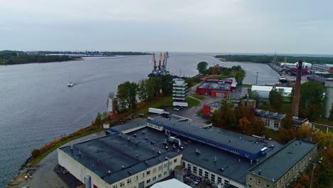 Aerial-drone-shot-over-godowns-alongside-a-port-situated-in-an-Inlet-with-a-container-terminal-on-a-cloudy-day