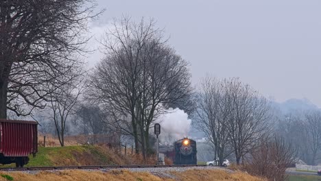 A-Long-View-of-a-Steam-Passenger-Train-Rounding-a-Bend,-Blowing-Smoke-Approaches-on-a-Winter-Day