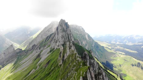Aerial-flyover-over-the-cliffs-of-Schafler-ridge-in-Appenzell,-Switzerland-towards-Altenturm-peak-on-a-cloudy-summer-day-with-a-view-of-one-of-Switzerland's-most-popular,-yet-dangerous-hiking-trails