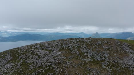 Distant-View-Of-Lone-Hiker-Walking-On-Rocky-Mountain-Peak-In-Luroy,-Norway