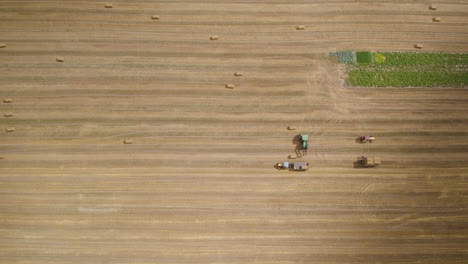Aerial-view-of-farmers-harvesting-hay-bales,-top-down-view-above-field