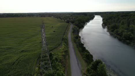 Electricity-power-lines-going-across-river-water-in-countryside,-drone-aerial