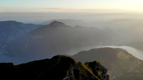 Aerial-flight-around-the-summit-of-Niederbauen-Chulm-on-a-golden-summer-morning-in-the-Swiss-Alps-with-a-view-of-Mythen,-Rigi,-Burgenstock,-Pilatus-and-cliffs-above-Lake-Lucerne