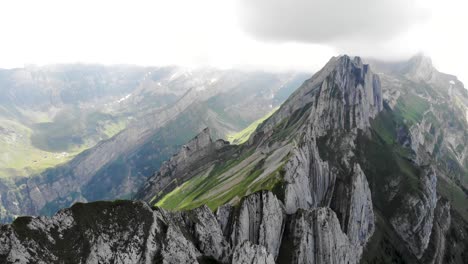Sobrevuelo-Aéreo-Sobre-Los-Acantilados-De-Schafler-Ridge-En-Appenzell,-Suiza-Con-Movimiento-De-Cámara-Panorámica-Hacia-Abajo-Que-Revela-Los-Acantilados-Y-La-Ruta-De-Senderismo-Sobre-La-Exuberante-Ladera-Verde-De-La-Montaña