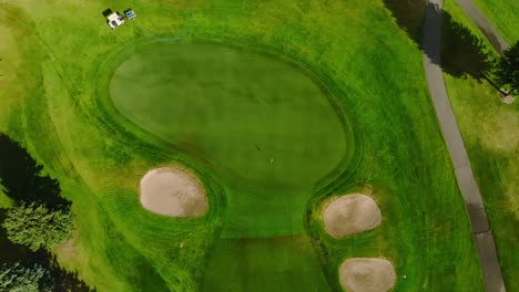 Top-down-drone-shot-of-a-golf-green-with-two-front-green-side-bunkers