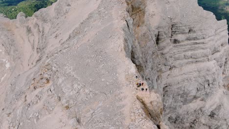Drone-top-down-shot-showing-group-of-hikers-arriving-peak-on-dangerous-edge-of-mountain