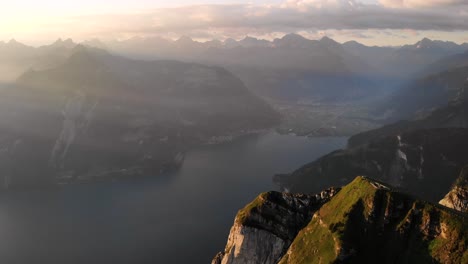 Luftaufnahme-Entlang-Der-Klippen-Bei-Niederbauen-Chulm-In-Uri,-Schweiz-Mit-Blick-Auf-Den-Vierwaldstättersee-Und-Seine-Fjorde-An-Einem-Goldenen-Sommermorgen-In-Den-Schweizer-Alpen