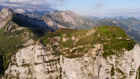 Aerial-view-of-Niederbauen-Chulm-on-a-golden-summer-morning-in-the-Swiss-Alps-with-a-spinning-view-from-the-peak's-cliffs-towards-the-fjords-of-Lake-Lucerne,-Uri,-Mythen-and-the-rising-sun
