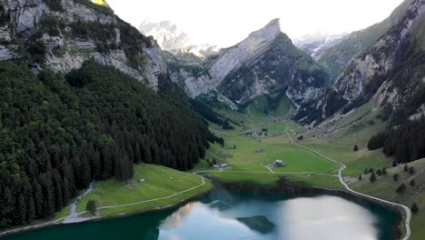 Aerial-flyover-over-lake-Seealpsee-in-Appenzell,-Switzerland-with-a-reflection-of-the-Alpstein-peaks-on-the-lake's-surface