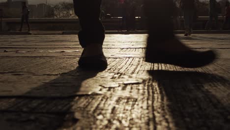 Ein-Mann-Geht-Während-Des-Sonnenuntergangs-über-Die-Straße,-Wobei-Das-Licht-Vom-Bürgersteig-Reflektiert-Wird