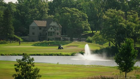 Golf-cart-parked-next-to-a-green-with-a-foreground-fountain-inside-a-pond