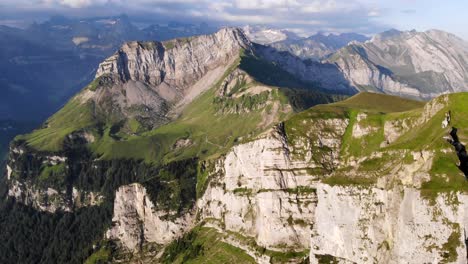 Luftaufnahme-Von-Niederbauen-Chulm-An-Einem-Goldenen-Sommermorgen-In-Den-Schweizer-Alpen-Mit-Einem-Sich-Drehenden-Blick-Auf-Die-Felsen-Des-Gipfels,-Die-Fjorde-Des-Vierwaldstättersees,-Uri,-Mythen-Und-Die-Aufgehende-Sonne
