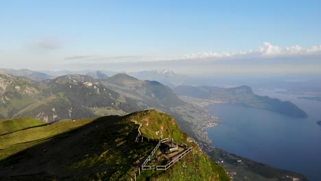 Aerial-flyover-over-Niederbauen-Chulm-in-Uri,-Switzerland-overlooking-Lake-Lucerne-with-a-view-of-Pilatus,-Burgenstock-and-the-summit's-cliffs-with-a-hiker-at-the-viewpoint