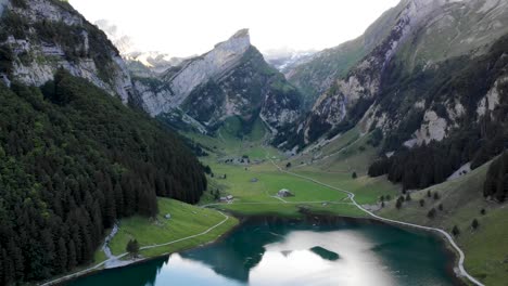 Aerial-flyover-over-lake-Seealpsee-in-Appenzell,-Switzerland-with-a-reflection-of-the-Alpstein-peaks-on-the-lake-with-reverse-motion-revealing-the-shores-and-the-lake's-end