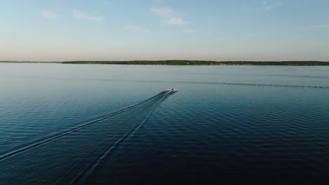 Drone-shot-following-a-jet-ski-on-a-large-lake-at-sunset