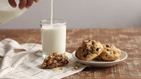 Eating-chocolate-chip-cookies-with-milk,-close-up-of-afro-american-dipping-cookies-in-a-glass-of-milk