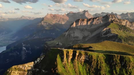 Spinning-flyover-around-the-summit-of-Niederbauen-Chulm-during-a-golden-summer-sunset-in-the-Swiss-Alps-with-a-view-of-the-fjords-of-Lake-Lucerne,-Mythen,-Rigi,-Burgenstock,-Pilatus