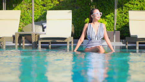 Schönes-Weibliches-Model-Im-Badeanzug,-Das-Im-Pool-Des-Luxuriösen-Tropischen-Resorts-Sitzt