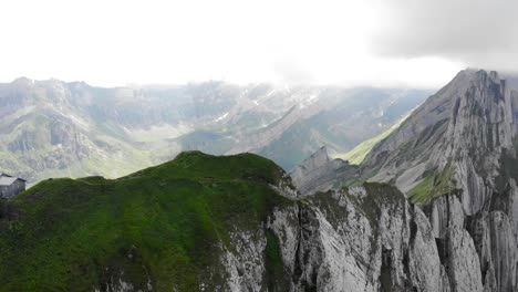 Sobrevuelo-Aéreo-Junto-A-La-Cresta-De-Schafler-En-Appenzell,-Suiza,-Desde-La-Cabaña-De-Schafler-Hacia-Alpenturm-Con-Acantilados,-Picos-De-Montaña-Y-Una-Exuberante-Ladera-Verde-De-Verano-A-La-Vista
