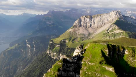 Aerial-flyover-over-the-summit-of-Niederbauen-Chulm-on-a-summer-morning-in-the-Swiss-Alps-with-a-view-of-the-peak's-cliffs-rotating-towards-Lake-Lucerne's-fjords