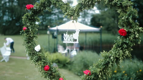 Mr-and-Mrs-Wedding-Sign-at-a-wedding-ceremony-decoration-hanging-from-a-heart-with-branches-and-flowers-reception