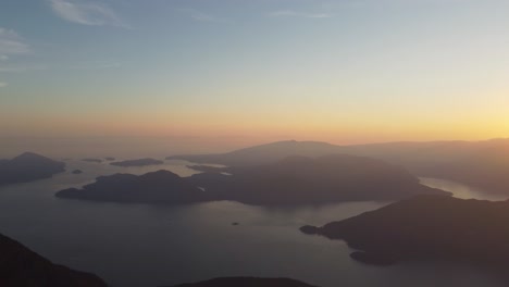 Sonnenuntergang-Luftdrohne-Von-Deeks-Peak-Mit-Felsiger-Landschaft-Des-Howe-Sound-Fjord-Mit-Blauem-Und-Orangefarbenem-Himmel-In-Pazifischen-Gebirgszügen-Kanada-Bc-4k