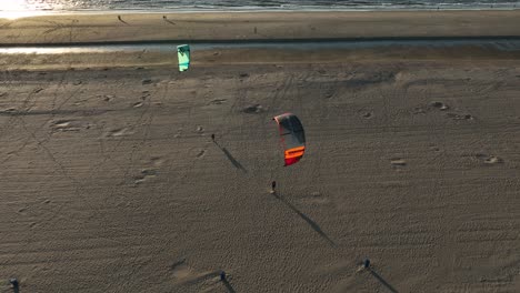Aerial-Drone-Shot-of-Kite-Surfers-After-Their-Session-Walking-on-The-beach-With-Their-Kites-In-The-Air
