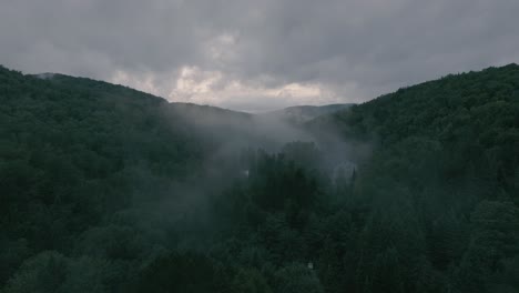 Drone-flying-through-a-beautiful-foggy-mountain-top-landscape,-valley-with-sunset