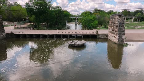 Round-Rock-Memorial-Park-Chisholm-Trail-Train-bridge-and-waterway-aerial-drone-push-in-close-up-on-the-round-rock-on-sunny-day-in-4k