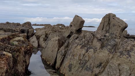 Slow-Panning-Shot-of-Sea-Rocks-Covered-in-Seaweed-to-Open-Sea-at-Lee-Bay-Beach-North-Devon-UK-4K