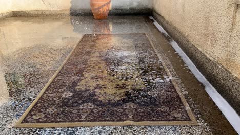 Rinsing-a-brown-carpet-with-water-on-a-terrace