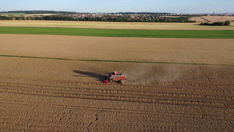 Grain-Harvester-in-Farming-Field,-Agricultural-Machine-Harvesting-Wheat-on-Sunny-Afternoon,-Drone-Aerial-View