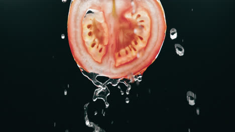 Wasser-Fließt-Frische-Tomatenscheibe-In-Zeitlupe-Mit-Hintergrundbeleuchtung-Auf-Schwarzem-Hintergrund