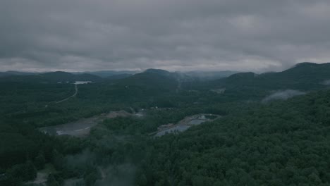 Drone-flying-through-a-beautiful-foggy-mountain-top-landscape,-valley-with-sunset,-water-filtration