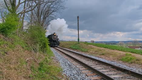 A-View-of-an-Antique-Restored-Steam-Passenger-Train-Approaching-Blowing-Steam-on-a-Spring-Day