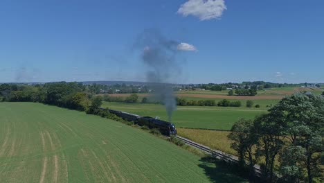 A-Drone-View-of-an-Antique-Steam-Passenger-Train-Coming-Around-a-Curve-in-Slow-Motion-Blowing-Smoke-and-Steam-Traveling-Thru-Fertile-Corn-Fields-on-a-Sunny-Summer-Day-1