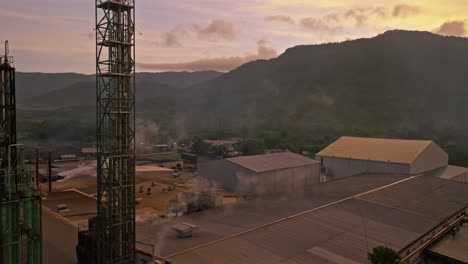 Aerial-flyover-industrial-factory-with-rising-fumes-in-Villa-Altagracia-at-colorful-dawn