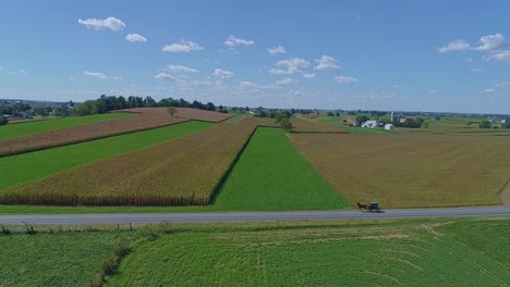Eine-Luftaufnahme-Von-Bauernhöfen,-Silos-Und-Ackerland,-Die-Bald-Mit-Einem-Amish-Pferd-Und-Einem-Buggy-Durchfahren-Werden-1
