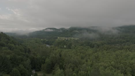 Drone-flying-through-a-beautiful-foggy-mountain-top-landscape,-over-a-river-3