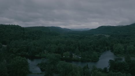 Drone-flying-through-a-beautiful-foggy-mountain-top-landscape,-valley-with-sunset-over-a-river